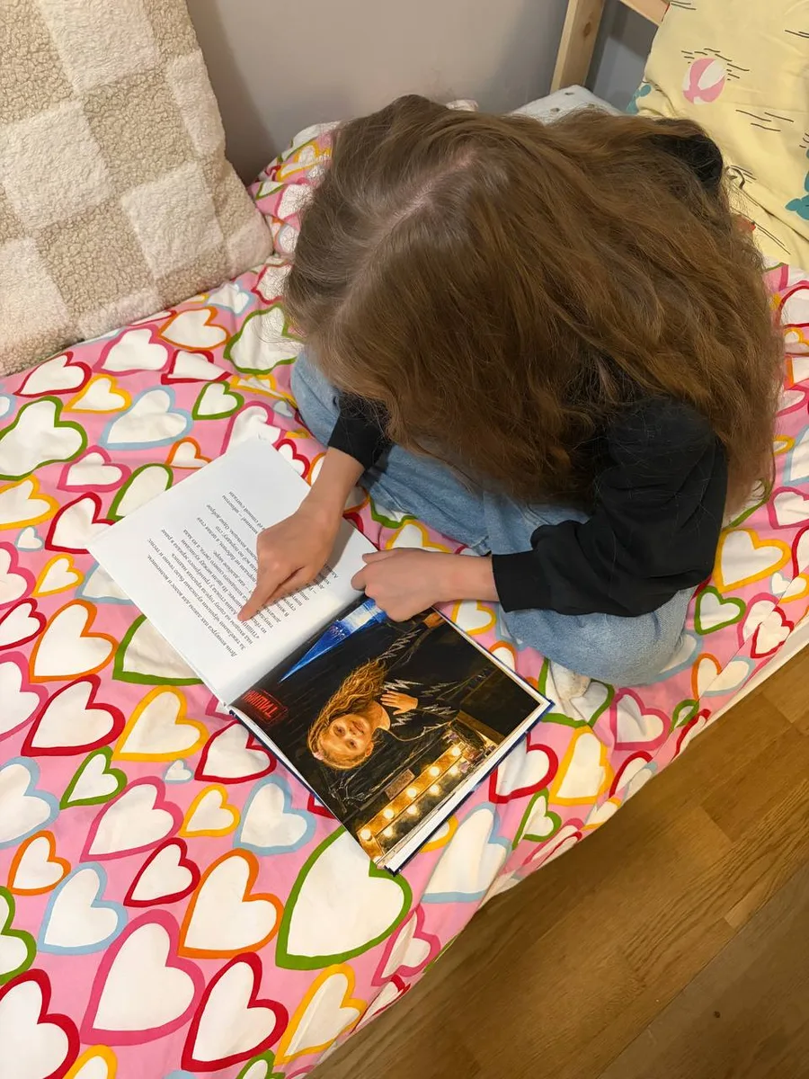 A girl lying on her bed reading her printed Booku hardcover