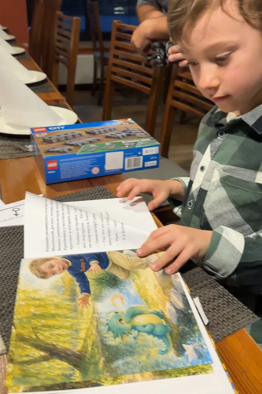A boy at a birthday table turning the pages of his Booku book
