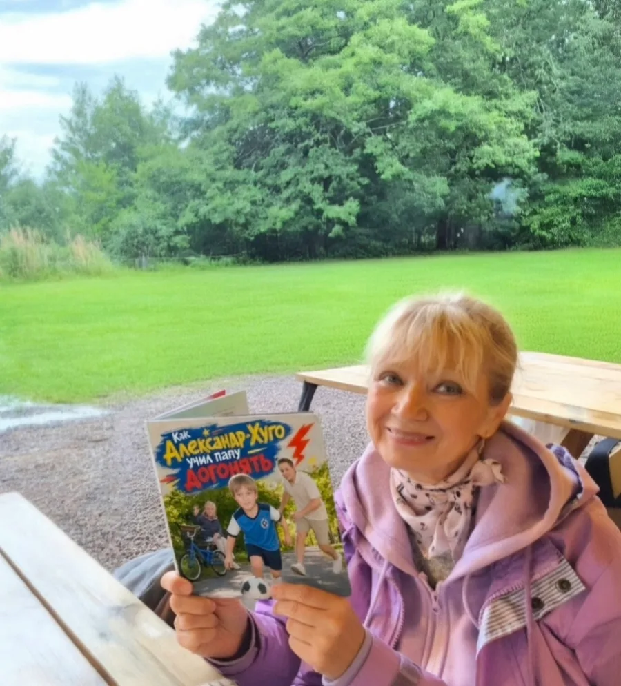 A grandmother on a veranda holding up her printed Booku book